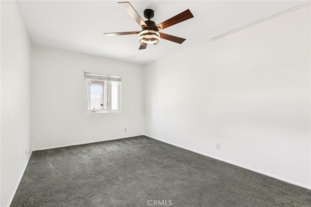 unfurnished room with a ceiling fan, baseboards, and dark colored carpet