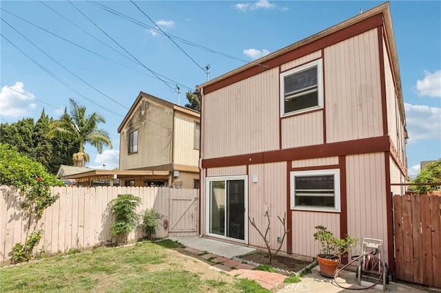 rear view of property with fence, a gate, a patio, and a lawn