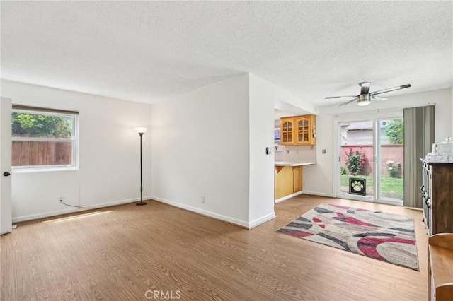 unfurnished living room featuring a textured ceiling, ceiling fan, and wood finished floors