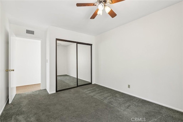 unfurnished bedroom featuring ceiling fan, visible vents, baseboards, a closet, and dark colored carpet