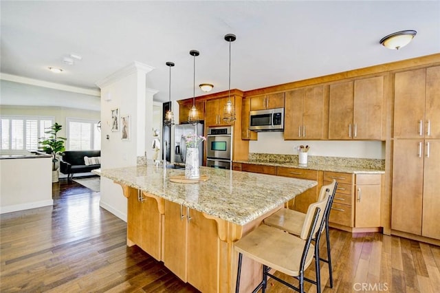 166 N Singingwood St Unit 9, Orange, CA 92869 - kitchen featuring brown cabinetry, dark wood-style flooring, a kitchen bar, light stone counters, and stainless steel appliances