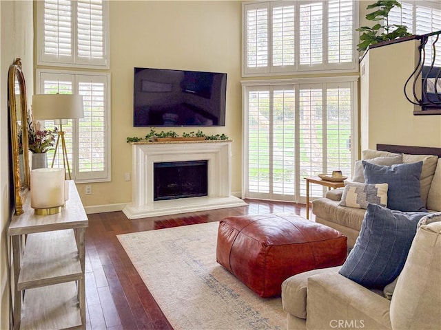 166 N Singingwood St Unit 9, Orange, CA 92869 - living area featuring a fireplace with raised hearth, a high ceiling, dark wood-style floors, and baseboards