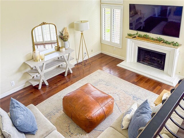 166 N Singingwood St Unit 9, Orange, CA 92869 - living room with baseboards, a fireplace with raised hearth, and wood finished floors