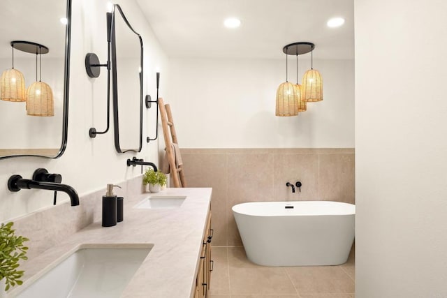 full bathroom featuring double vanity, a freestanding bath, tile patterned flooring, a sink, and recessed lighting