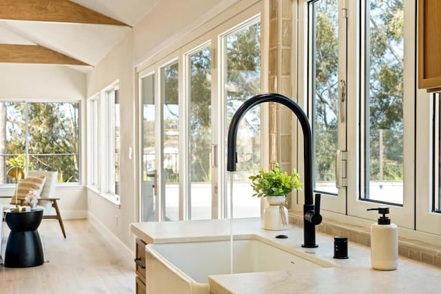 interior space with a sink, baseboards, and lofted ceiling