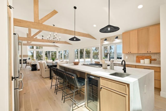 kitchen with wine cooler, light brown cabinetry, open floor plan, lofted ceiling with beams, and a sink