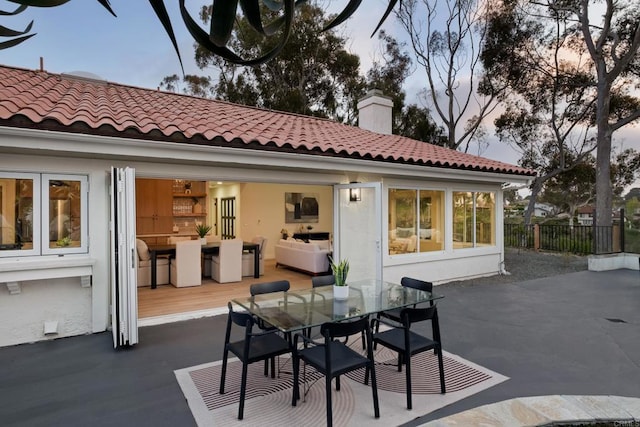 rear view of house with a tiled roof, fence, outdoor dining space, and a patio area
