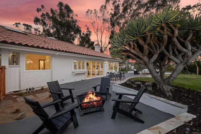 patio terrace at dusk featuring a fire pit and outdoor dining area