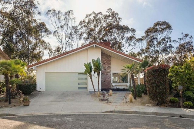 view of front of home featuring concrete driveway, an attached garage, and a chimney