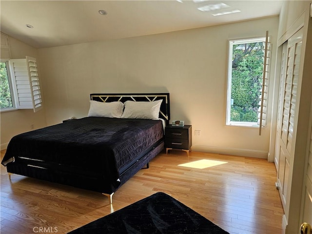 bedroom with baseboards, lofted ceiling, and light wood-type flooring