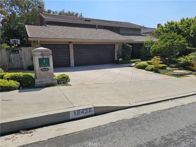 traditional-style home featuring concrete driveway, stucco siding, a tile roof, and a garage