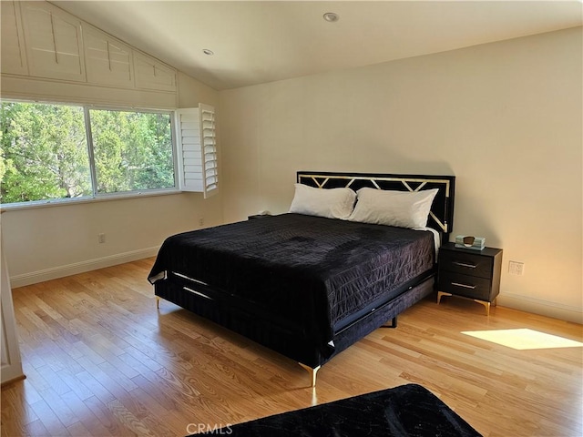 bedroom featuring light wood-style floors, baseboards, and vaulted ceiling