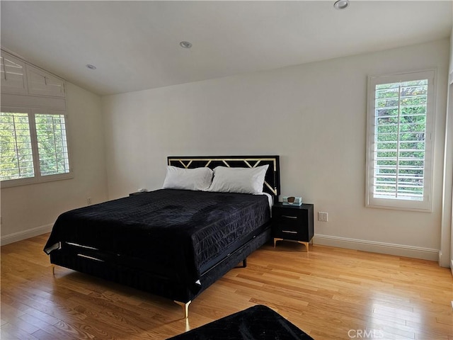 bedroom with light wood-type flooring, baseboards, and multiple windows