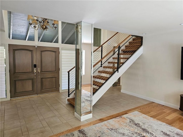 entryway featuring an inviting chandelier, light wood-style flooring, baseboards, and stairway
