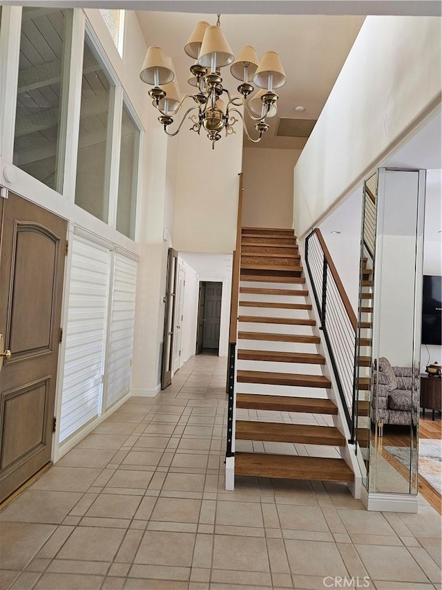 staircase with an inviting chandelier, a wealth of natural light, tile patterned flooring, and a towering ceiling