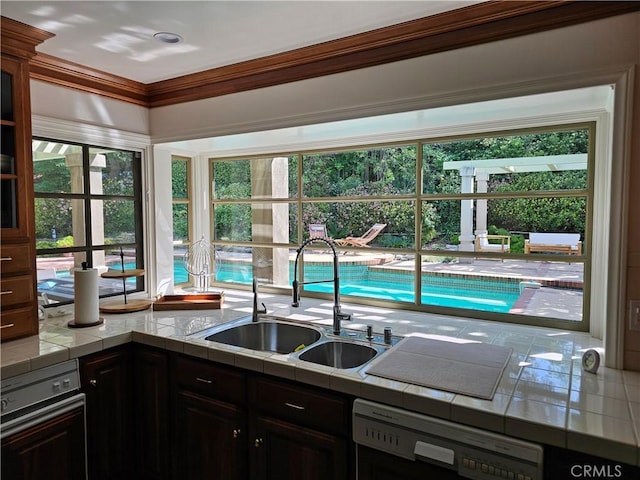 kitchen with tile counters, a sink, plenty of natural light, and dishwasher