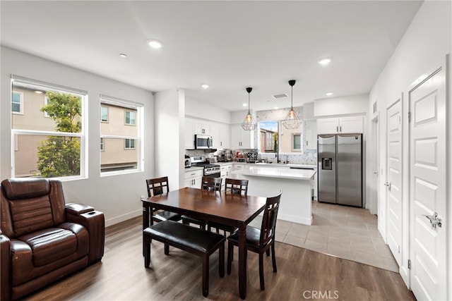 dining room with recessed lighting, baseboards, and light wood finished floors