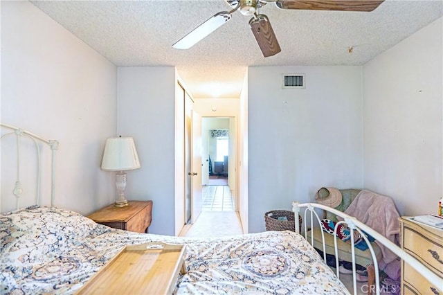 bedroom with a textured ceiling, visible vents, and ceiling fan
