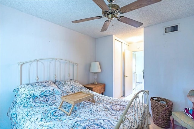 bedroom featuring visible vents, a ceiling fan, and a textured ceiling