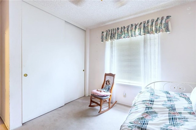 carpeted bedroom with a textured ceiling, multiple windows, and a closet