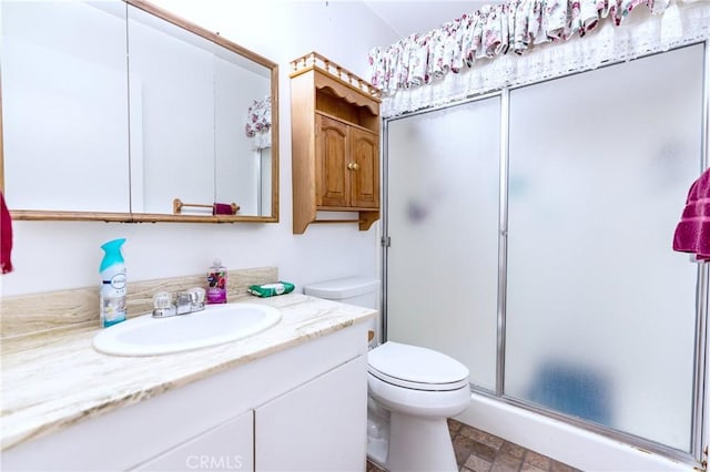 bathroom with toilet, a shower stall, and vanity