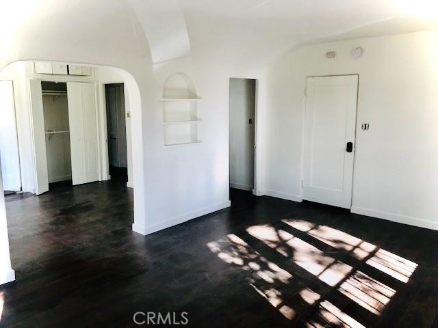 2853 Buckingham Rd, Los Angeles, CA 90016 - interior space with built in features, arched walkways, vaulted ceiling, baseboards, and dark wood-style floors