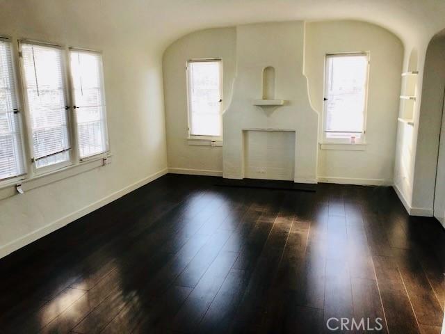 2853 Buckingham Rd, Los Angeles, CA 90016 - unfurnished living room with baseboards, arched walkways, and dark wood-style flooring