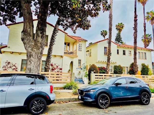 2853 Buckingham Rd, Los Angeles, CA 90016 - view of front of house featuring a tiled roof, fence, a balcony, and stucco siding