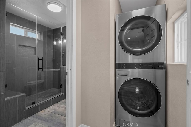 washroom featuring laundry area, stacked washer and clothes dryer, and wood finished floors