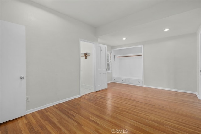 unfurnished bedroom featuring baseboards, recessed lighting, wood finished floors, and a closet