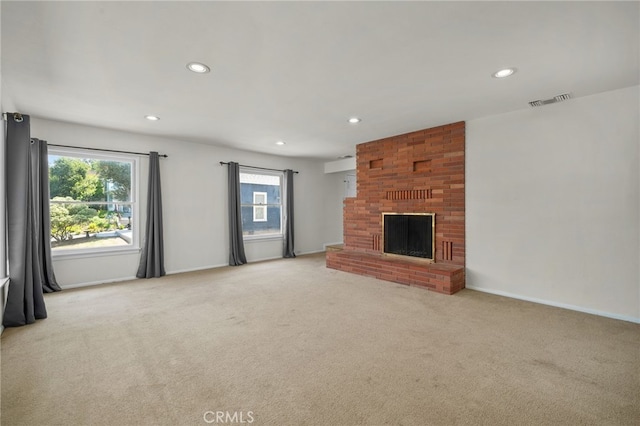 unfurnished living room with a brick fireplace, light colored carpet, visible vents, and recessed lighting
