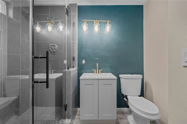 bathroom with vanity, a textured wall, a stall shower, and toilet