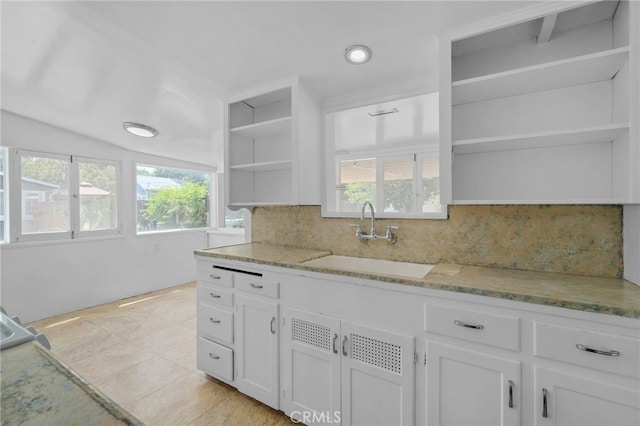 kitchen with open shelves, a sink, white cabinets, and light stone countertops