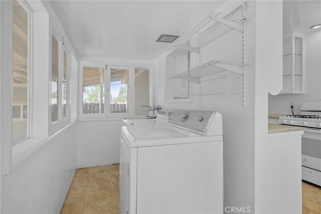 laundry area featuring a sink, light tile patterned floors, laundry area, and independent washer and dryer