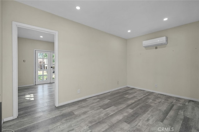 unfurnished room with recessed lighting, baseboards, wood finished floors, and a wall mounted air conditioner