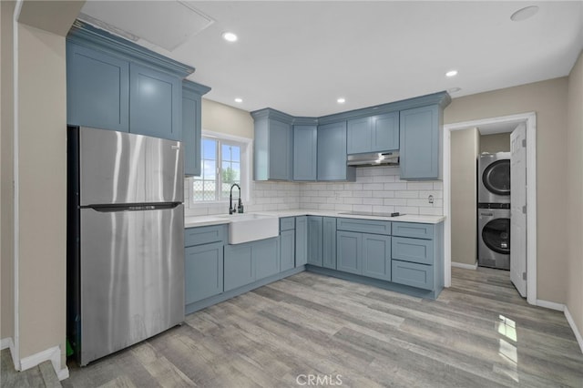 kitchen featuring freestanding refrigerator, under cabinet range hood, and blue cabinets