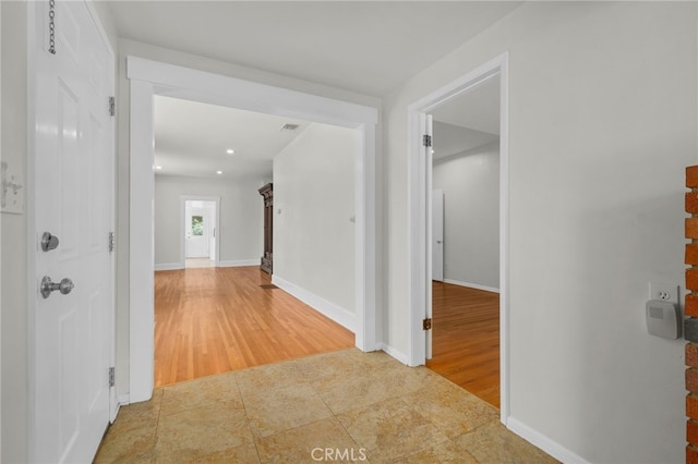 hall with baseboards, recessed lighting, wood finished floors, and visible vents