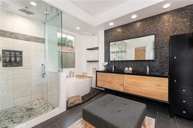 full bath with double vanity, recessed lighting, a soaking tub, and a stall shower