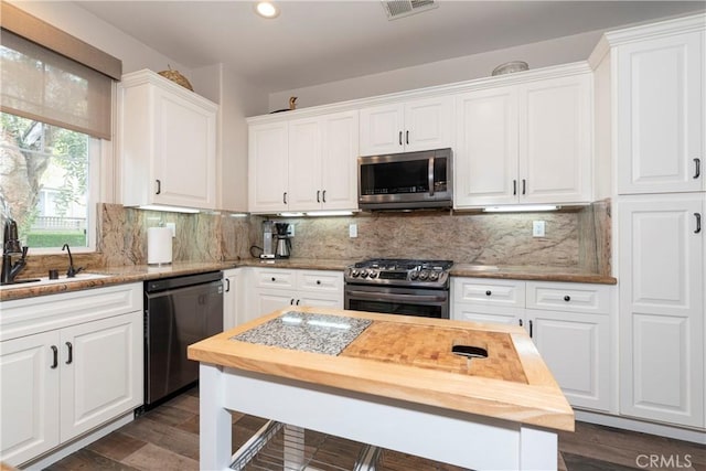 kitchen with visible vents, appliances with stainless steel finishes, a sink, white cabinets, and butcher block countertops
