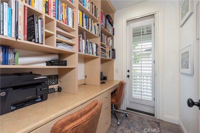 home office featuring baseboards, built in desk, and wood finished floors