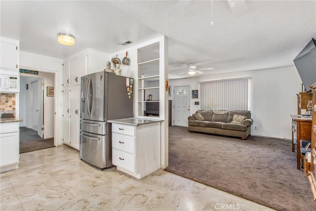 kitchen featuring stainless steel fridge with ice dispenser, ceiling fan, light carpet, and white cabinetry