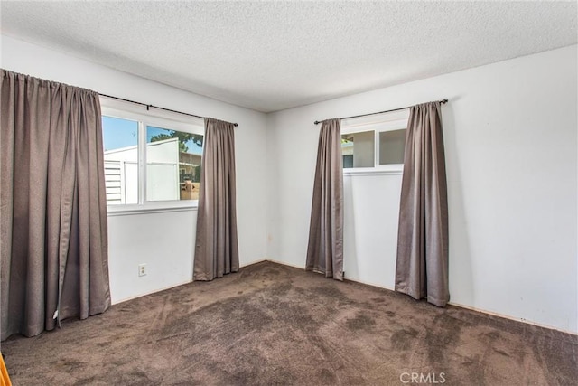 carpeted empty room featuring a textured ceiling
