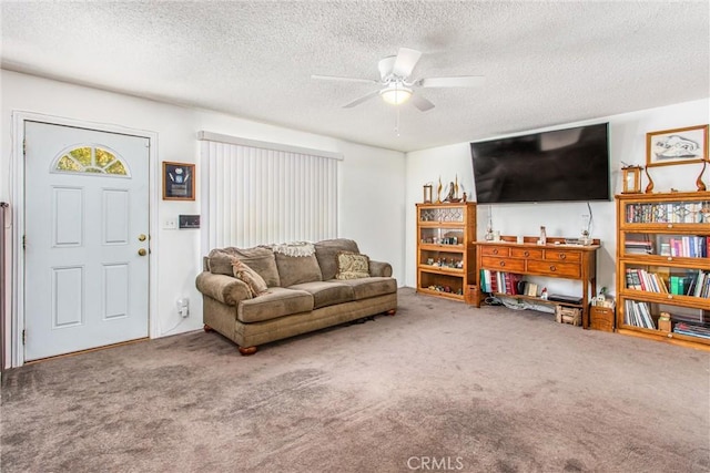 carpeted living room featuring a ceiling fan and a textured ceiling