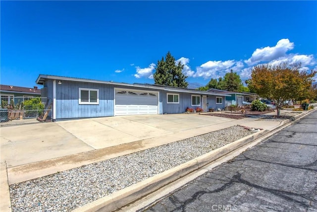 ranch-style house with concrete driveway, an attached garage, and fence