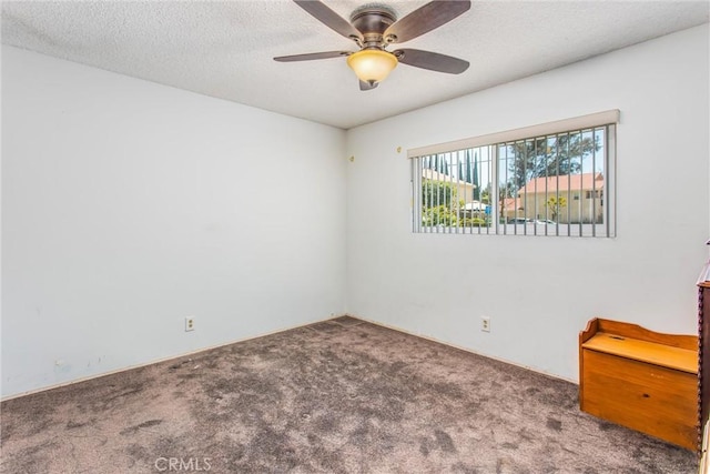 carpeted empty room featuring a ceiling fan and a textured ceiling