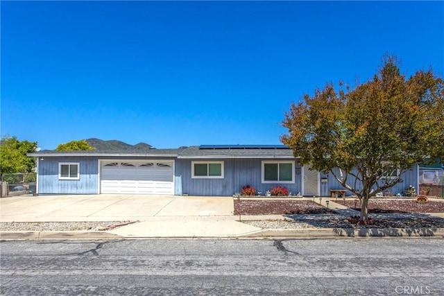 view of front of property with driveway, fence, roof mounted solar panels, and a garage