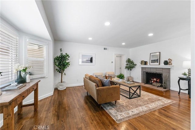 living room featuring baseboards, a brick fireplace, recessed lighting, and wood finished floors