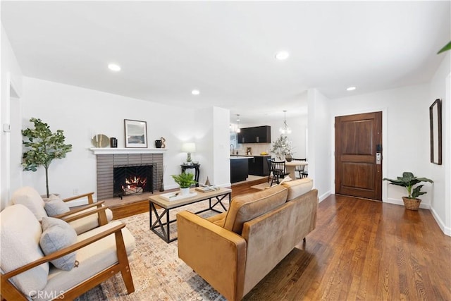 living room featuring a brick fireplace, recessed lighting, baseboards, and wood finished floors