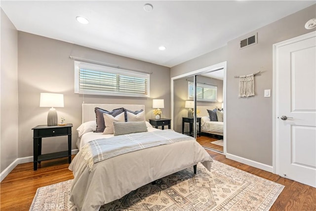 bedroom featuring baseboards, visible vents, wood finished floors, and a closet