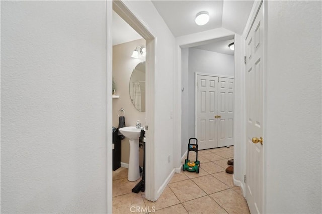 corridor featuring baseboards and light tile patterned flooring